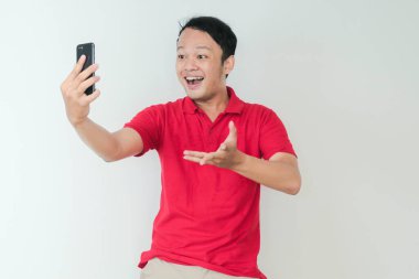 Genç Asyalı adam, gri arka planda gördüğü şey karşısında şok olmuş ve mutlu..