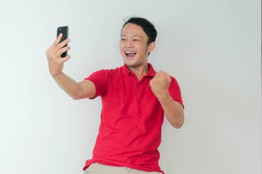 Genç Asyalı adam, gri arka planda gördüğü şey karşısında şok olmuş ve mutlu..