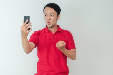 Genç Asyalı adamın yüzü, gri arka planda akıllı telefonda gördüklerini şok etti..