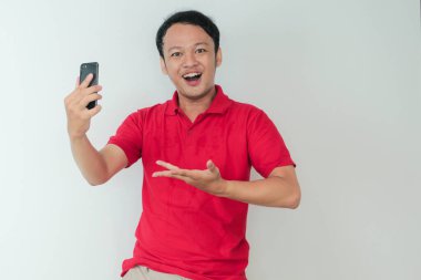 Genç Asyalı adam, gri arka planda gördüğü şey karşısında şok olmuş ve mutlu..