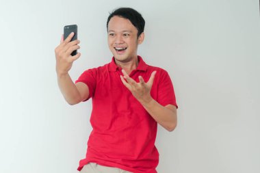 Genç Asyalı adam, gri arka planda gördüğü şey karşısında şok olmuş ve mutlu..