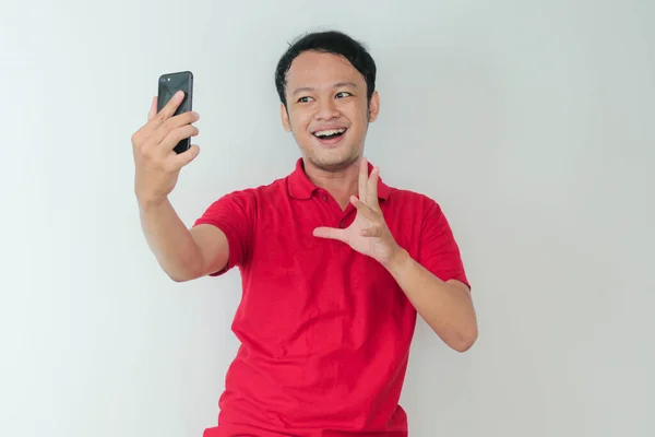 Genç Asyalı adam, gri arka planda gördüğü şey karşısında şok olmuş ve mutlu..