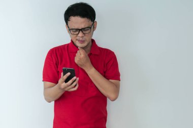 Akıllı genç Asyalı adamın stüdyo arka planında akıllı telefon görünce kafası karışıyor ve strese giriyor..