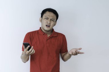 Akıllı genç Asyalı adamın stüdyo arka planında akıllı telefon görünce kafası karışıyor ve strese giriyor..