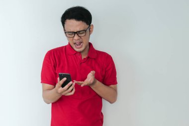 Akıllı genç Asyalı adamın stüdyo arka planında akıllı telefon görünce kafası karışıyor ve strese giriyor..