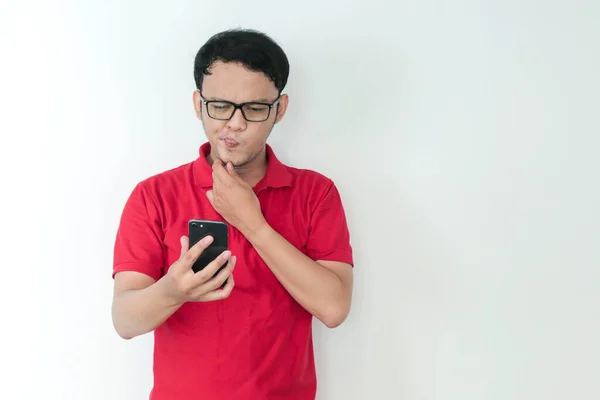 スマート若いアジアの男は混乱していると強調しているときにスタジオの背景にスマートフォンを見る — ストック写真