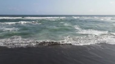 Sahildeki dalgaların havadan görünüşü. Koyu kumlu dalgalar. Mavi turkuaz temiz dalgalı deniz suyu.
