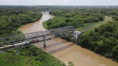 Endonezya, Yogyakarta 'da Progo Nehri üzerindeki tren köprüsünden geçen trenin hava görüntüsü..