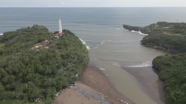 灯台と伝統的なボートでインドネシアのグヌンキドゥルの男爵ビーチの空中ビュー — ストック動画