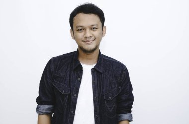 Beyaz gömlek ve kot pantolon giyen gülümseyen Asyalı genç adamın portresi..