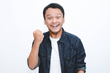 Mutlu ve gülümseyen Asyalı genç adam başarı ve başarıyı kutlamak için kolunu kaldırıyor..