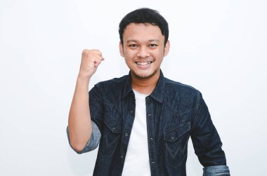 Mutlu ve gülümseyen Asyalı genç adam başarı ve başarıyı kutlamak için kolunu kaldırıyor..