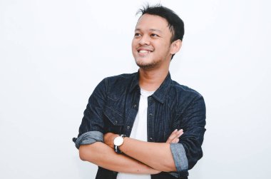 Beyaz gömlek ve kot pantolon giyen gülümseyen Asyalı genç adamın portresi..