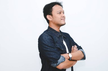 Beyaz gömlek ve kot pantolon giyen gülümseyen Asyalı genç adamın portresi..