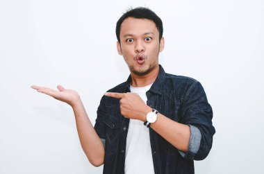 Genç Asyalı adam şaşırdı ve haykırdı vay canına sağ elini gri arka planda tek başına gösterdi..