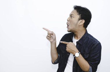 Genç Asyalı adam şaşırdı ve haykırdı vay canına sağ elini gri arka planda tek başına gösterdi..