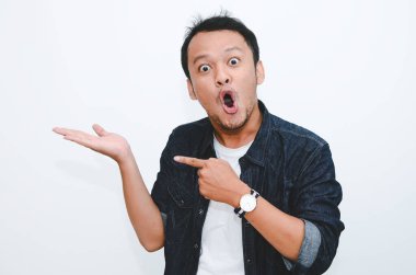 Genç Asyalı adam şaşırdı ve haykırdı vay canına sağ elini gri arka planda tek başına gösterdi..