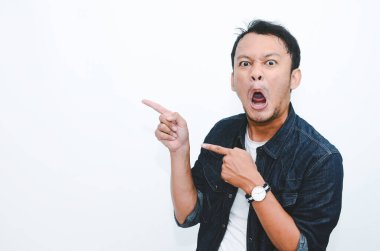 Genç Asyalı adam şaşırdı ve haykırdı vay canına sağ elini gri arka planda tek başına gösterdi..