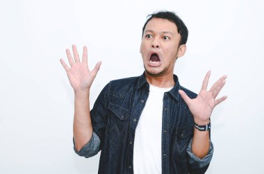 Genç Asyalı adam şaşırdı ve haykırdı vay canına sağ elini gri arka planda tek başına gösterdi..