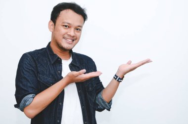 Beyaz tişörtlü, eli boş Asyalı genç adamın gülümsemesi.