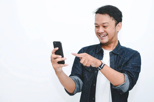 携帯電話でゲームをプレイするときに若いアジアの男の笑顔と幸せな顔 — ストック写真