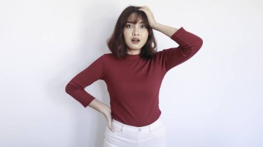 Kafası karışmış ve korkmuş Asyalı güzel kız beyaz arka planda kırmızı gömlekli.