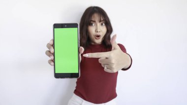Wow ve Şok Asyalı güzel kız yeşil ekranlı telefonu işaret ediyor. Yüzü bulanık ve beyaz.