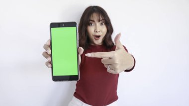 Wow ve Şok Asyalı güzel kız yeşil ekranlı telefonu işaret ediyor. Yüzü bulanık ve beyaz.