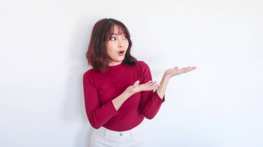 Şok edici Asyalı güzel kız beyaz arka planda kırmızı gömlekli kızı işaret ediyor.