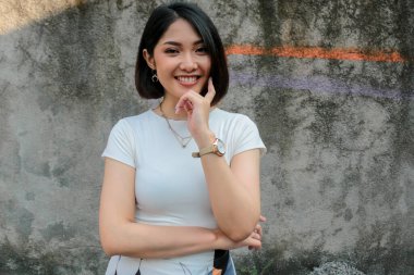 Beyaz arka planda beyaz gömlekli Asyalı güzel bir kızın jestini düşünüyorum.