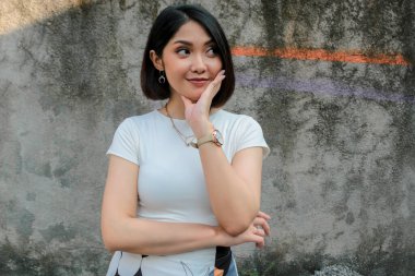 Beyaz arka planda beyaz gömlekli Asyalı güzel bir kızın jestini düşünüyorum.