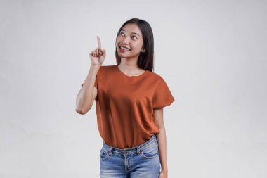 Kahverengi gömlekli neşeli genç Asyalı kadın beyaz arka planla izole edilmiş fotokopi odasını işaret ediyor..