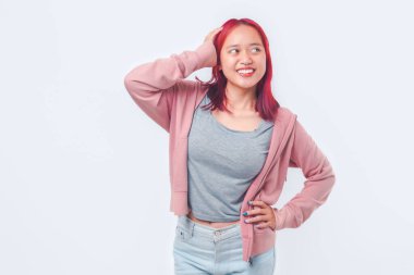 Pembe ceketli mutlu Asyalı genç kız, izole edilmiş beyaz arka planda gülümserken başını tutuyor..