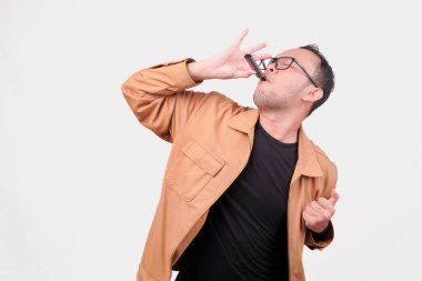 Heyecanlı genç Asyalı adam beyaz arka planla izole edilmiş fotokopi alanını işaret ederken elektrikli sigara içiyor..