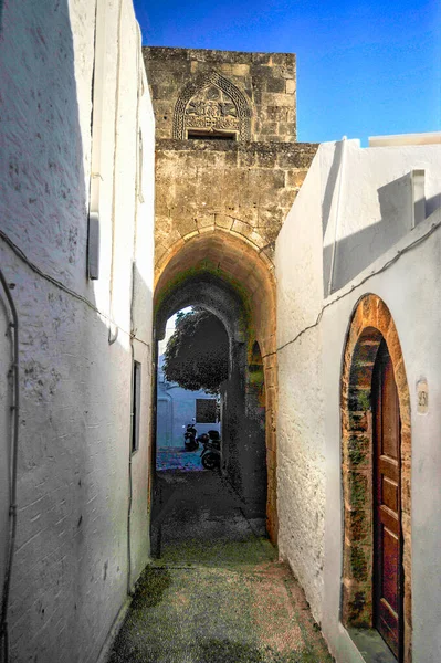 The small town of Lindos hides behind the mighty rock of the acropolis separating two coves with sandy beaches