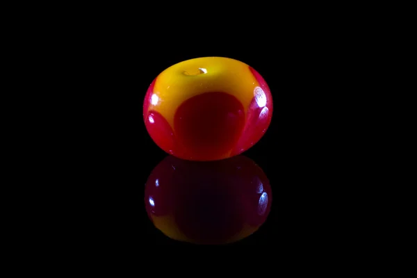 Red and yellow glassy bead with reflection — Stock Photo, Image