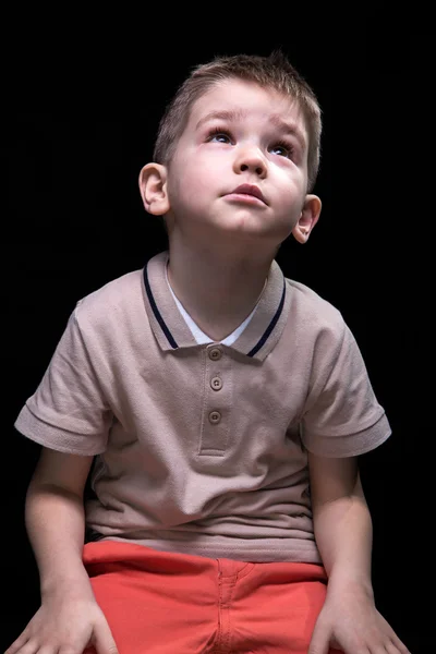 Niño rubio sentado mirando hacia arriba —  Fotos de Stock