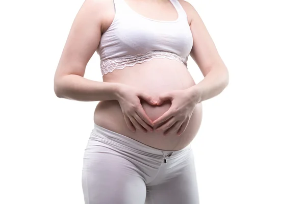 Беременная молодая женщина и сердце на животе — стоковое фото