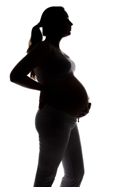Silhouet van zwangere vrouw knuffelen buik — Stockfoto
