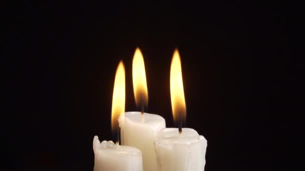 Кадри спалювання трьох свічок на чорному тлі — стокове відео