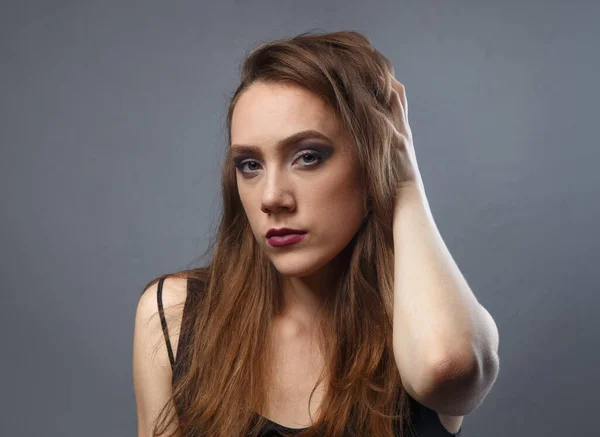 Portrait of woman touching her hair with purple lips on grey background — Stock Photo, Image