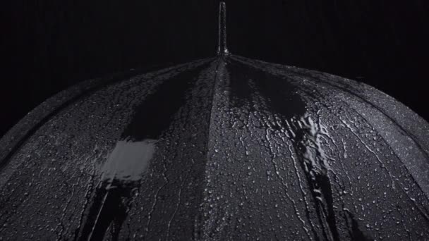 Filmación de paraguas negro y gotas de agua sobre fondo negro — Vídeo de stock