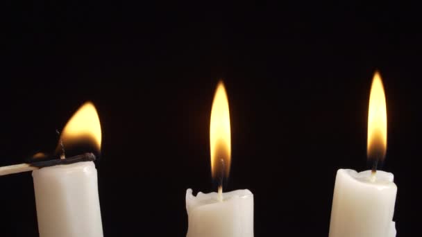 Video zapalování bílých svíček na černém pozadí — Stock video