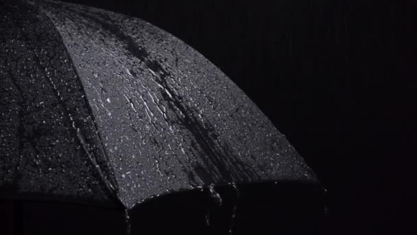 Black umbrella and raindrops on black background — Stock Video