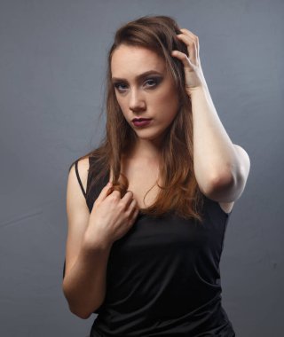 Gri arkaplanda mor dudaklı bir kadının saçına dokunuşu.