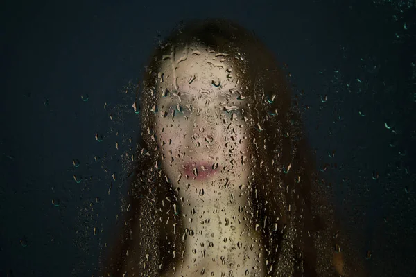 Image d'une jeune femme derrière un verre avec des gouttes d'eau — Photo