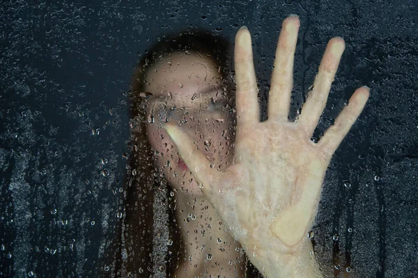 Photo de jeune femme touchant le verre avec des gouttes d'eau — Photo