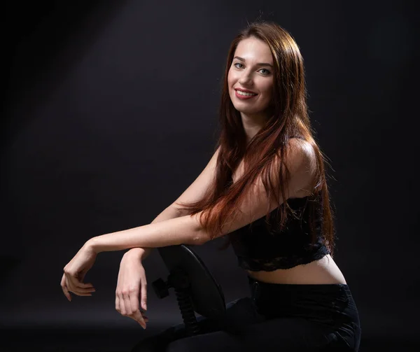 Foto di giovane seduta donna con i capelli lunghi su sfondo scuro — Foto Stock