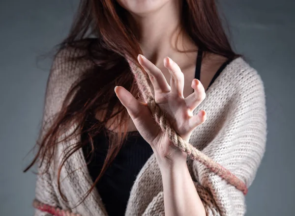 Photo d'une jeune femme attachée avec une corde à la main sur fond gris — Photo