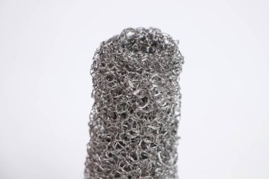 Beyaz zemin üzerinde yuvarlanmış gri metal örgülü ızgaranın fotoğrafı